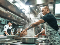 This is a dynamic photograph captured inside a busy, professional kitchen environment.