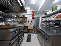 The image presents an interior view of a well-organized, spacious commercial kitchen or food preparation area.