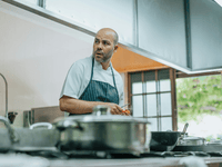This image is a portrait of a chef in a professional kitchen. He is a man