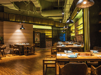 The image depicts the dimly lit and warmly decorated interior of a modern restaurant or dining establishment.