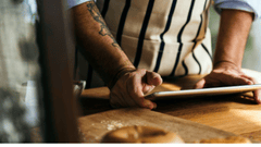 the image shows a chef using a tablet in the kitchen.