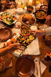 A photograph of people gathered for a dinner with various foods.