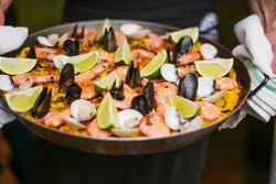 A dish of paella with shrimp, mussels, and lemon