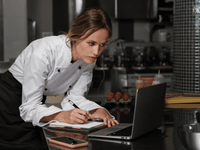 The image shows a female chef or restaurant professional working in a commercial kitchen setting.