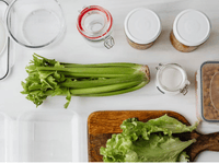Fresh vegetables and sealed containers neatly arranged on a clean surface for a food hygiene inspection in a commercial kitchen.