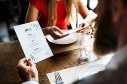 Image of a couple reviewing the menu at a restaurant, highlighting dishes and meal options. Moments of relaxation and appreciation of gastronomy.