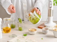 Making homemade pesto with fresh ingredients using a mixer in a modern kitchen, highlighting natural basil sauce.